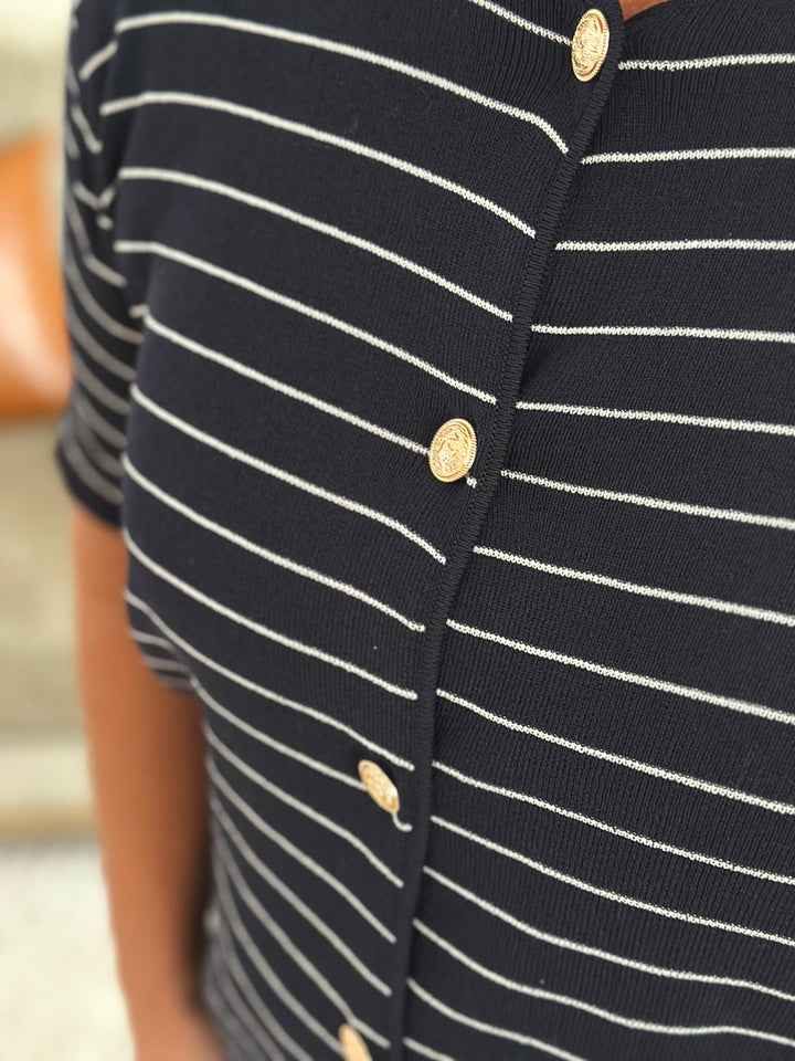 Close-up of a black and white striped shirt with gold buttons.