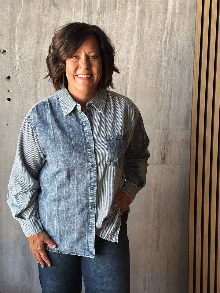 Person wearing a denim shirt against a wooden panel background