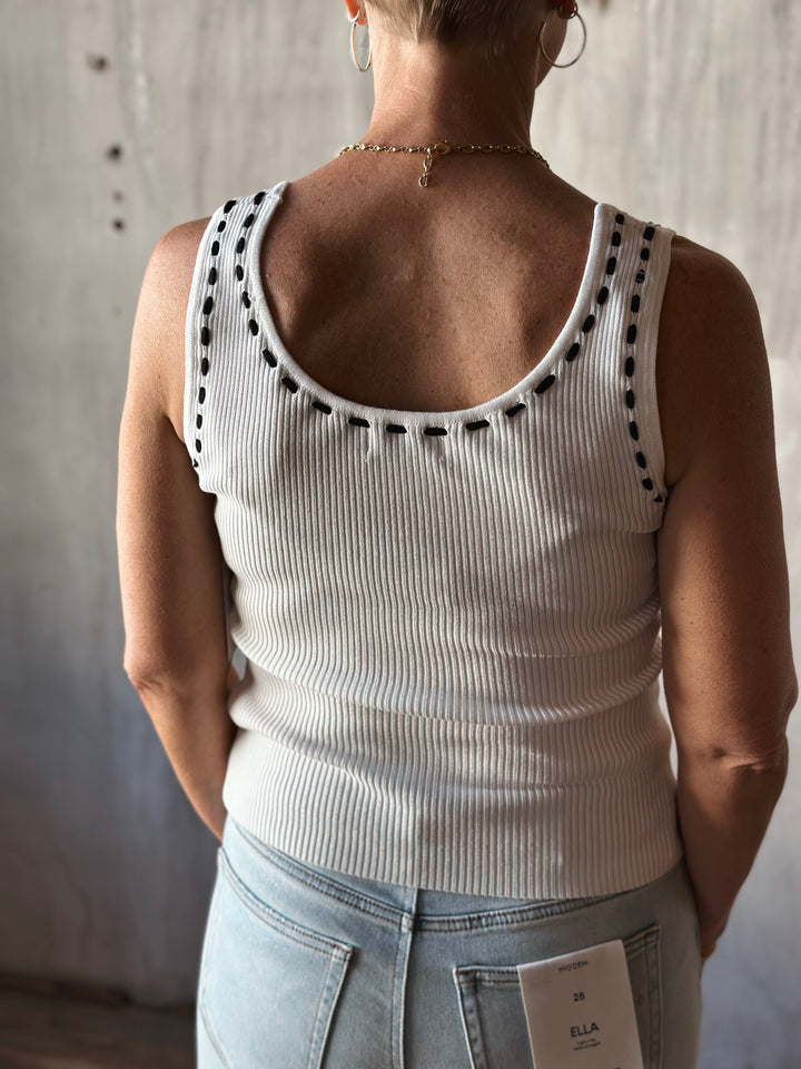 back view of sleeveless sweater knit tank features a flattering scoop neckline and a playful front tie detail. Cream top with black bow. 
