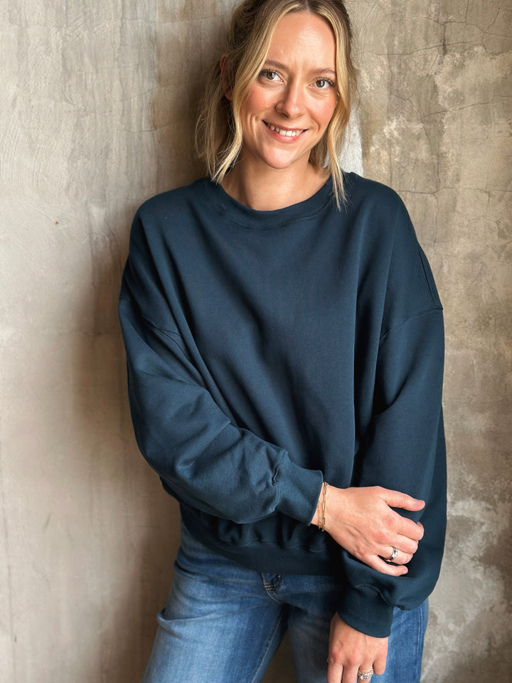 Woman wearing a navy blue sweater against a textured wall
