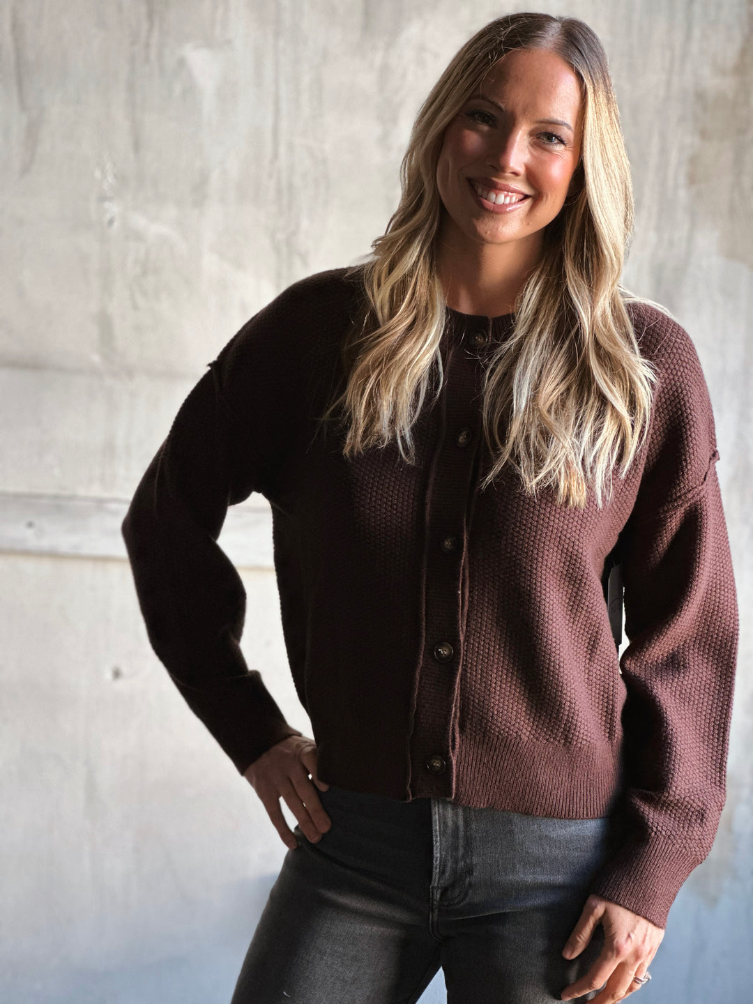 Woman wearing a brown cardigan against a light gray background