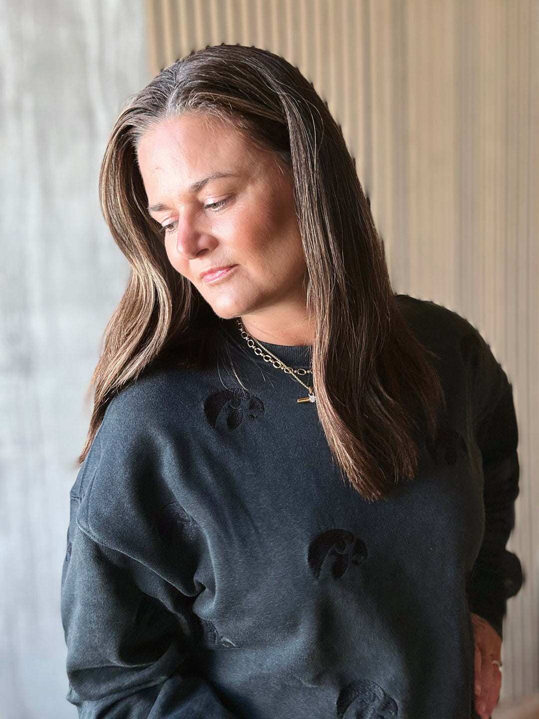 Woman wearing a dark gray sweatshirt with black bear designs, standing indoors.
