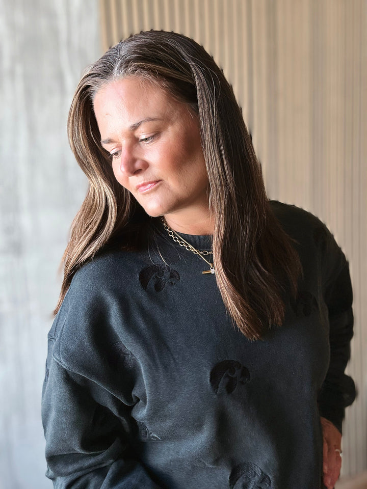 Woman wearing a dark gray sweatshirt with black bear designs, standing indoors.