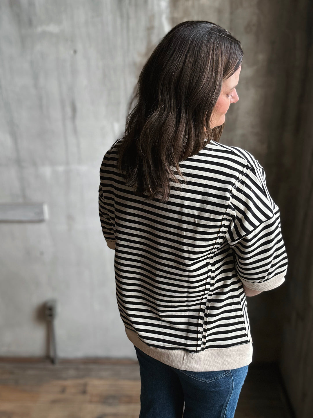 Person wearing a black and white striped shirt against a concrete wall.