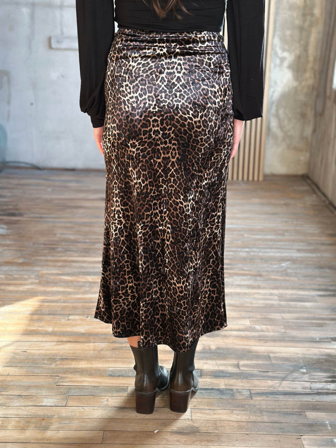 Person wearing a leopard print skirt with a plain background