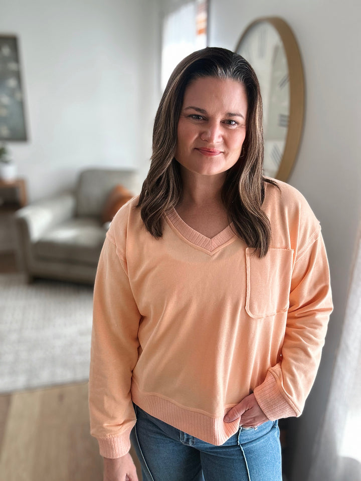 Woman wearing a peach sweater in a living room setting