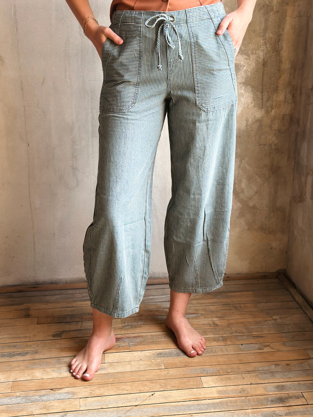 Person wearing checkered pants standing on a wooden floor with a neutral wall background