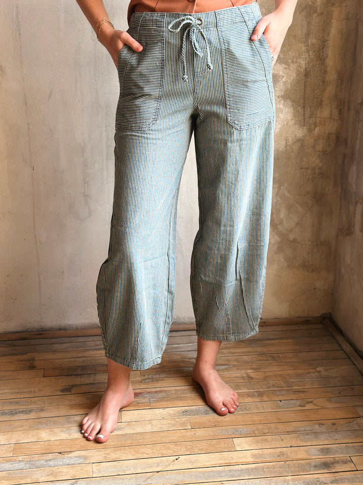 Person wearing checkered pants standing on a wooden floor with a neutral wall background