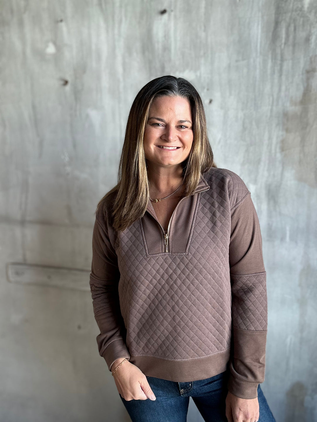 Woman in a mocha brown quilted half-zip pullover and jeans, front view