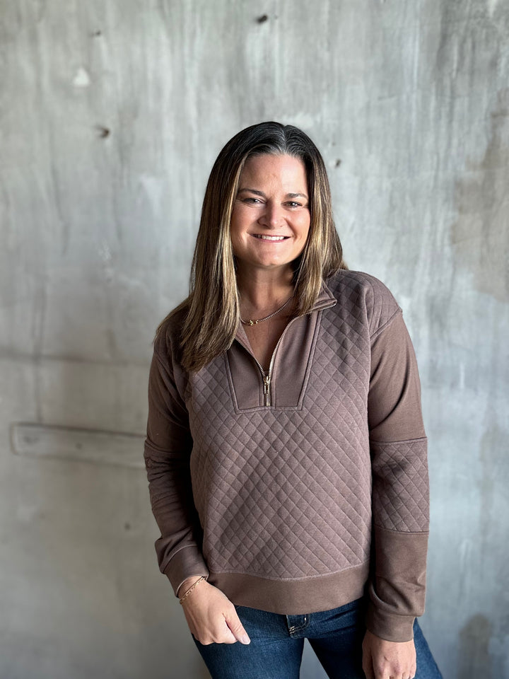 Woman in a mocha brown quilted half-zip pullover and jeans, front view