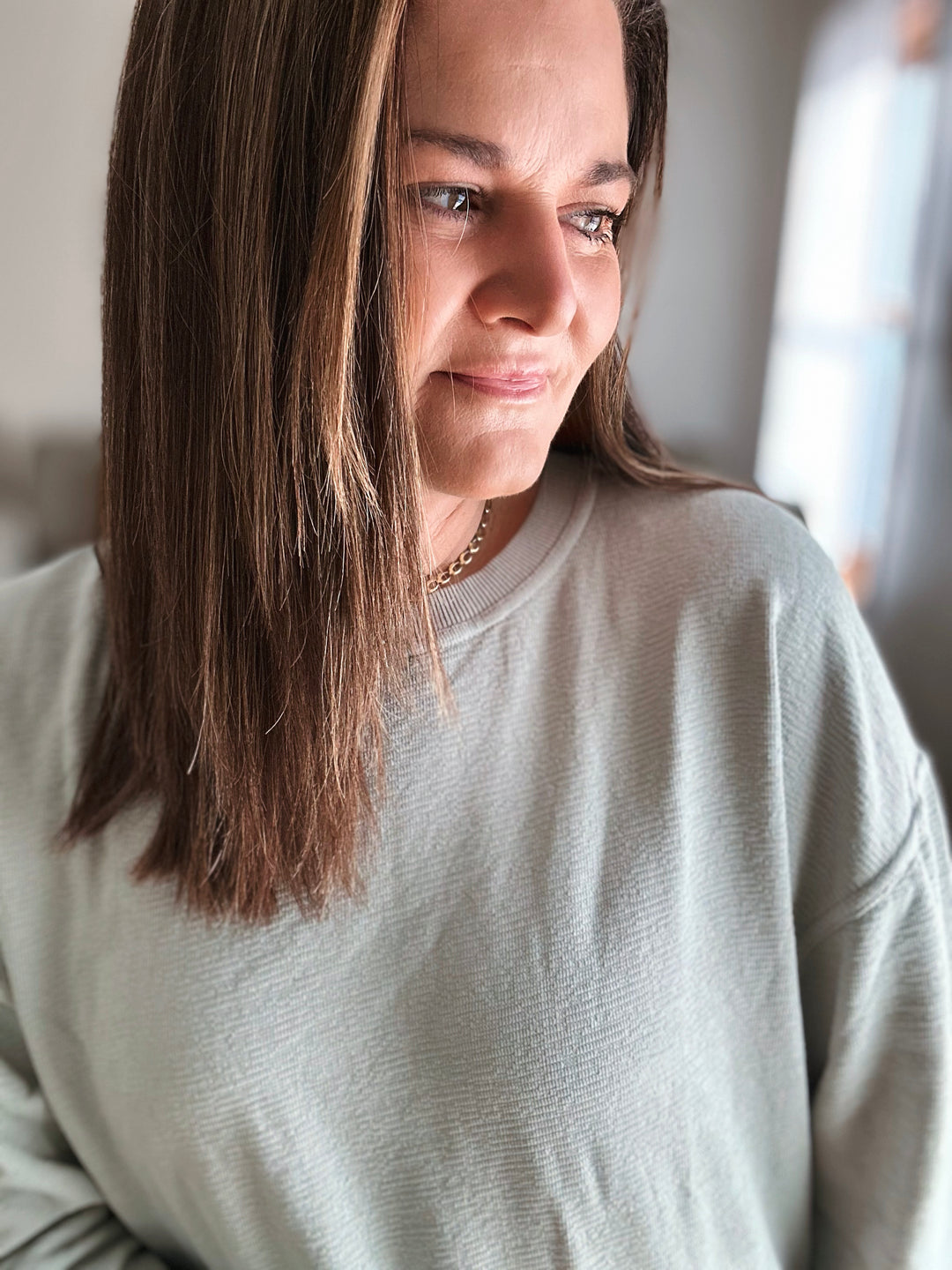 Woman wearing a light gray sweater indoors