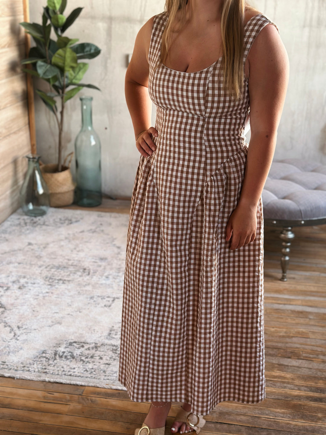 A woman wearing a brown and white plaid dress in a home setting.