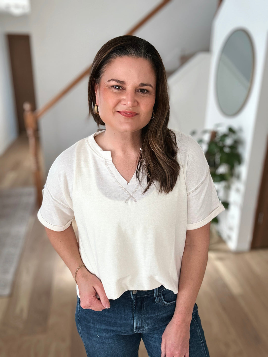 Woman wearing a white t-shirt and blue jeans indoors