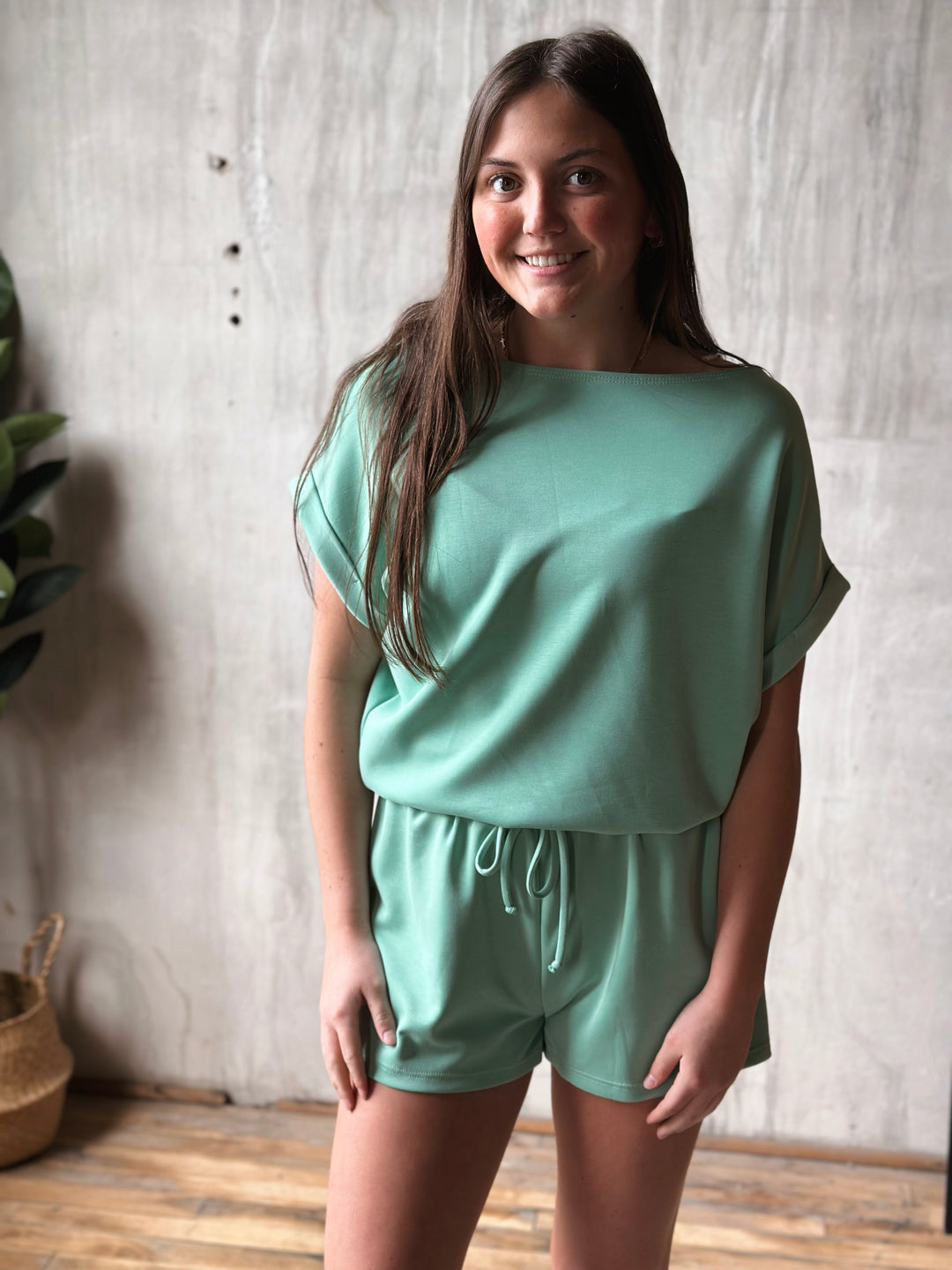 Woman wearing a mint green outfit standing against a neutral wall.