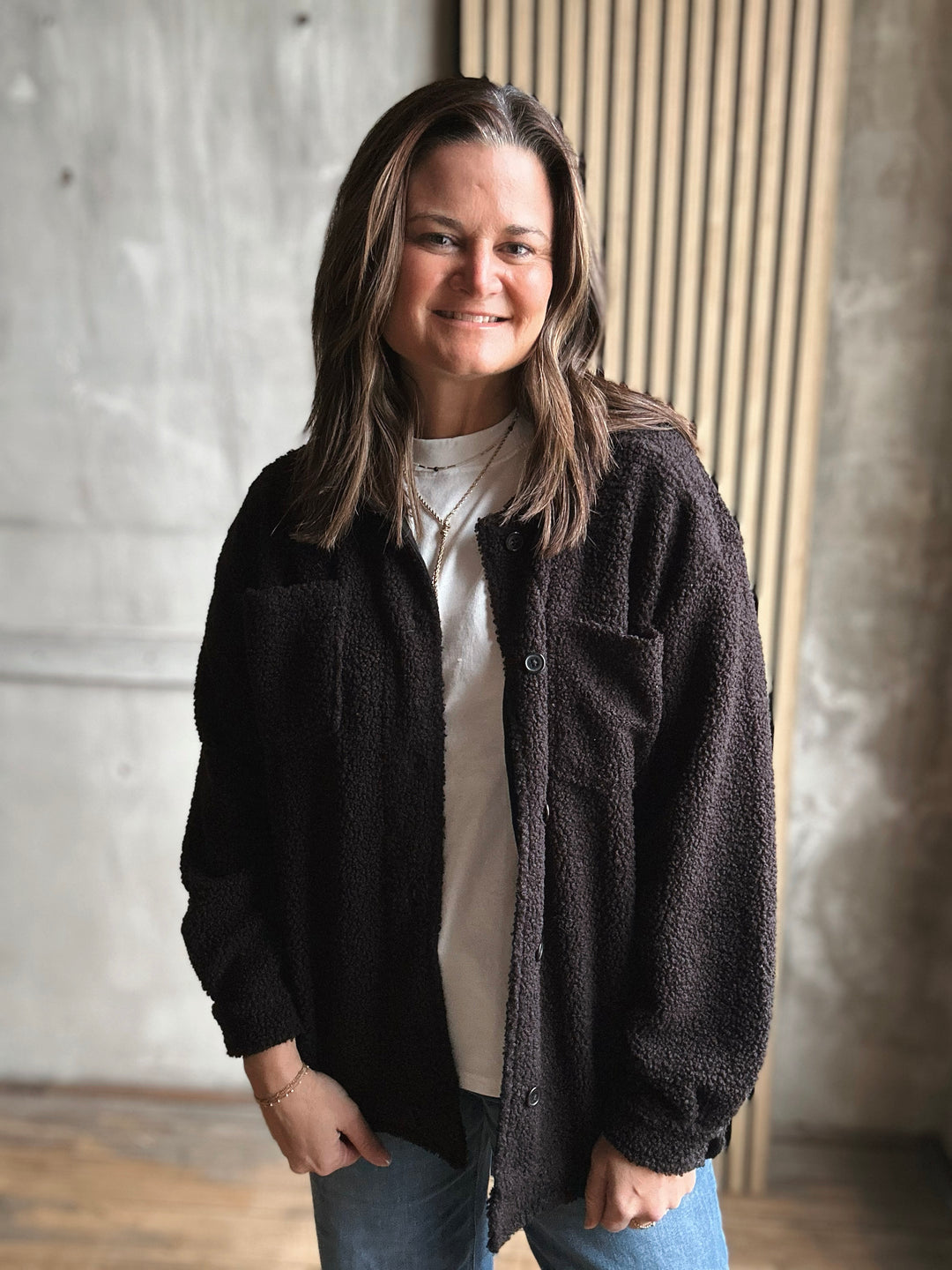 Person wearing a black jacket over a white shirt in an indoor setting