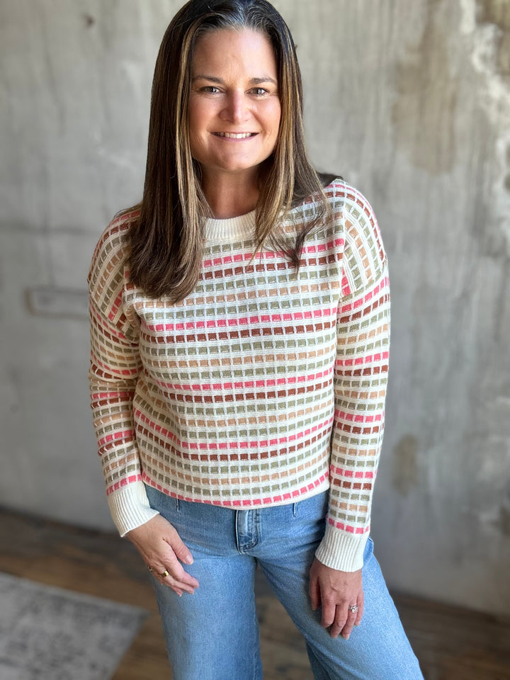 Cream multicolor striped sweater tucked slightly into light-wash jeans