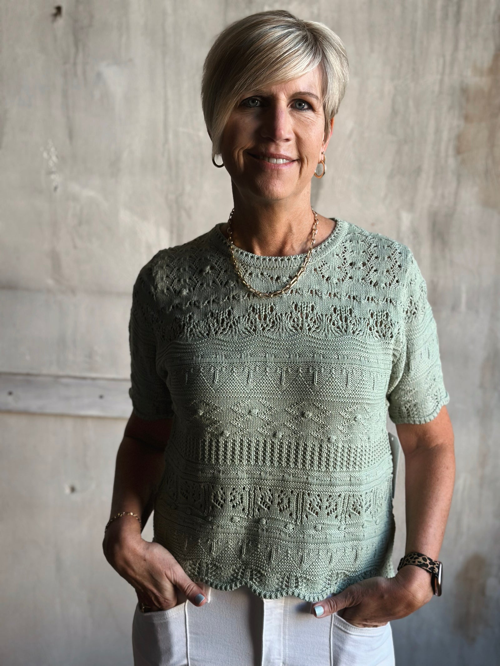 Woman wearing a light green knitted sweater against a plain background