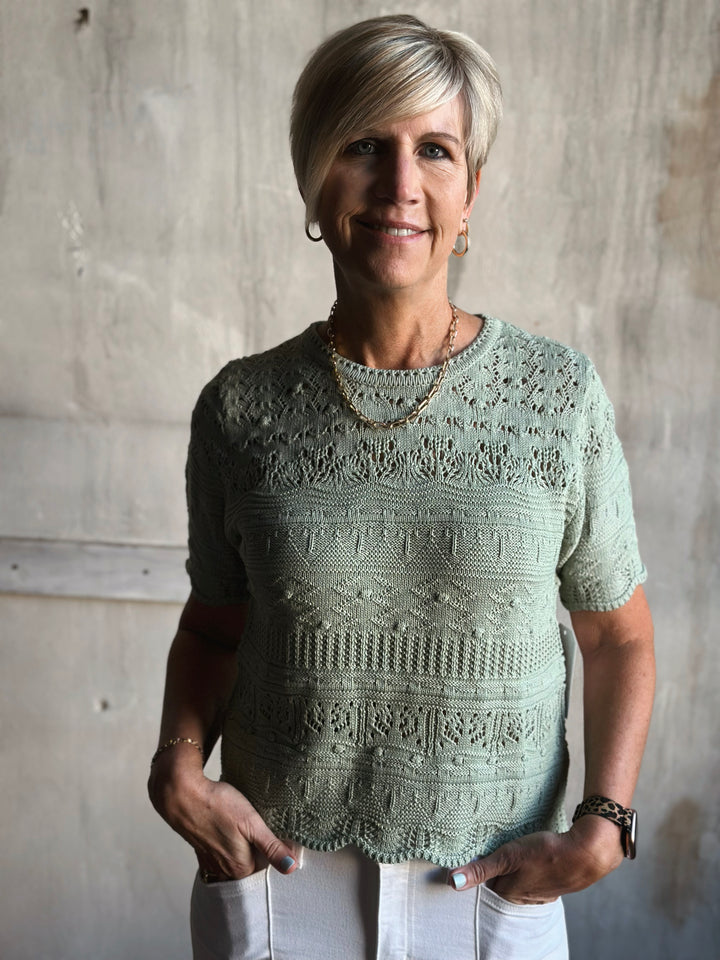 Woman wearing a light green knitted sweater against a plain background