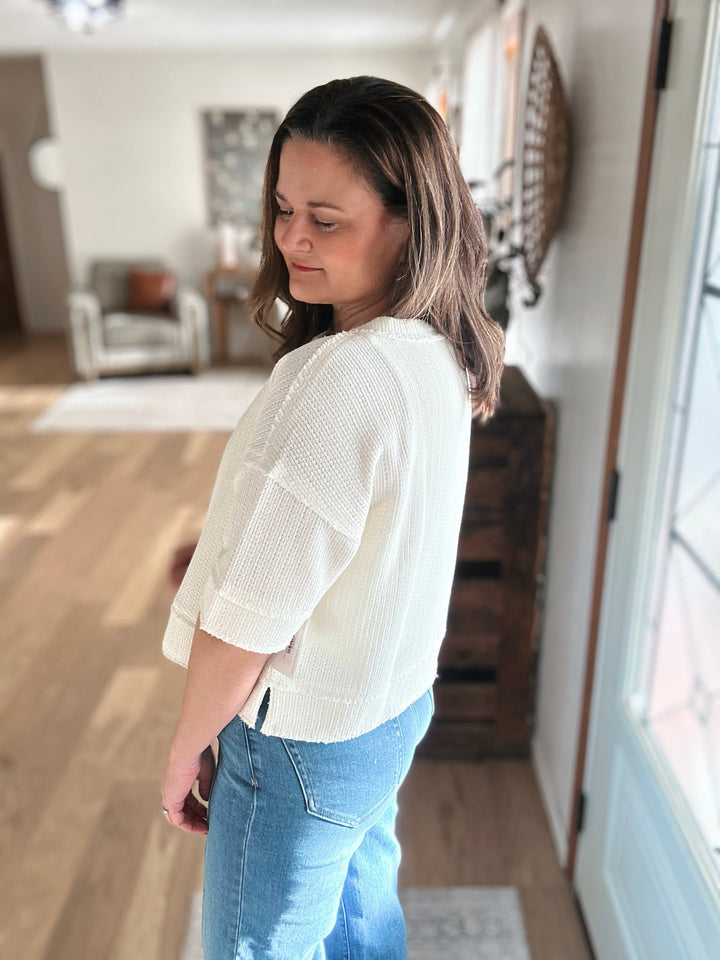 Woman wearing a white blouse and blue jeans indoors