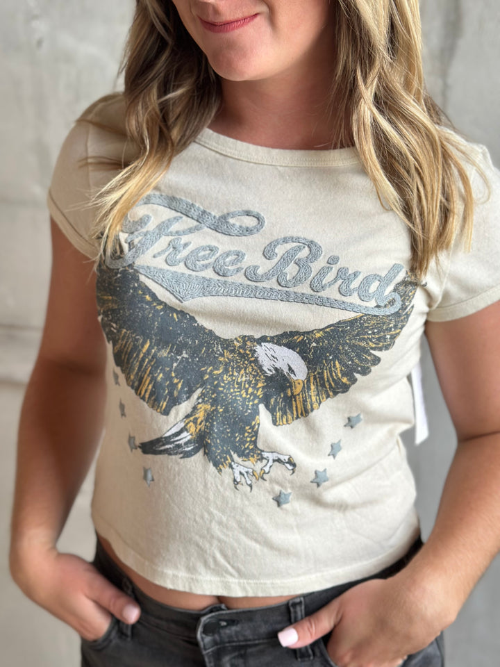 Cream Free Bird eagle graphic tee worn with gray jeans