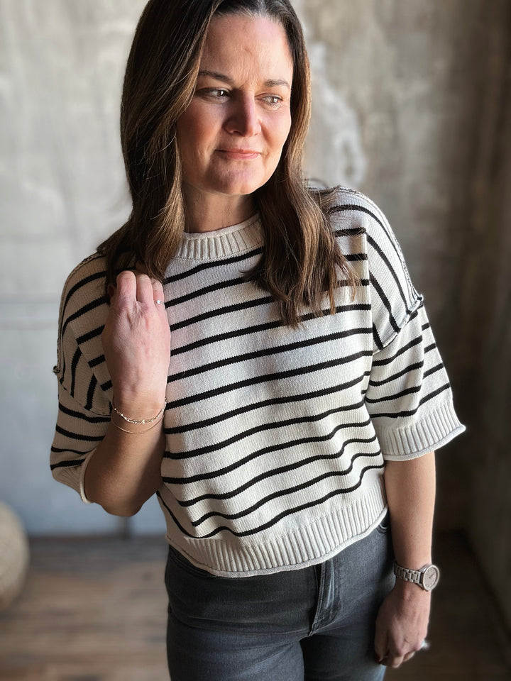 Woman wearing a black and white striped sweater in an indoor setting