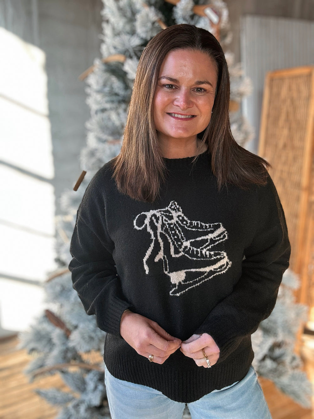 Woman wearing a black sweater with a white skeleton design, standing in a room with decorative elements.
