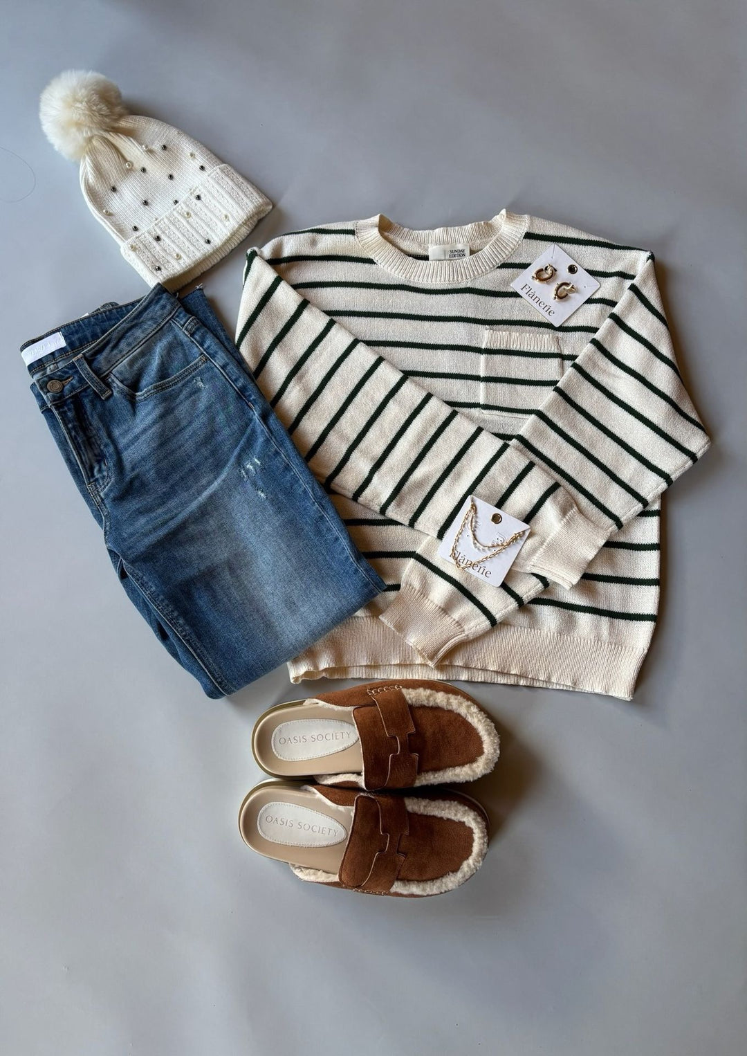 Children's outfit with striped shirt, jeans, hat, and shoes on a gray surface