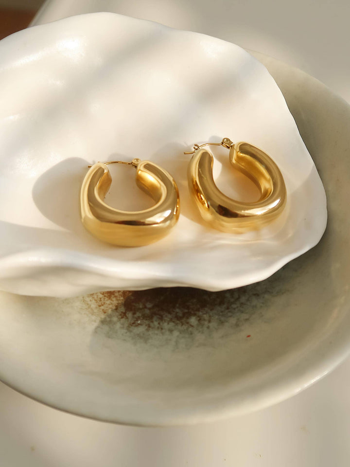 Gold hoop earrings on a white shell