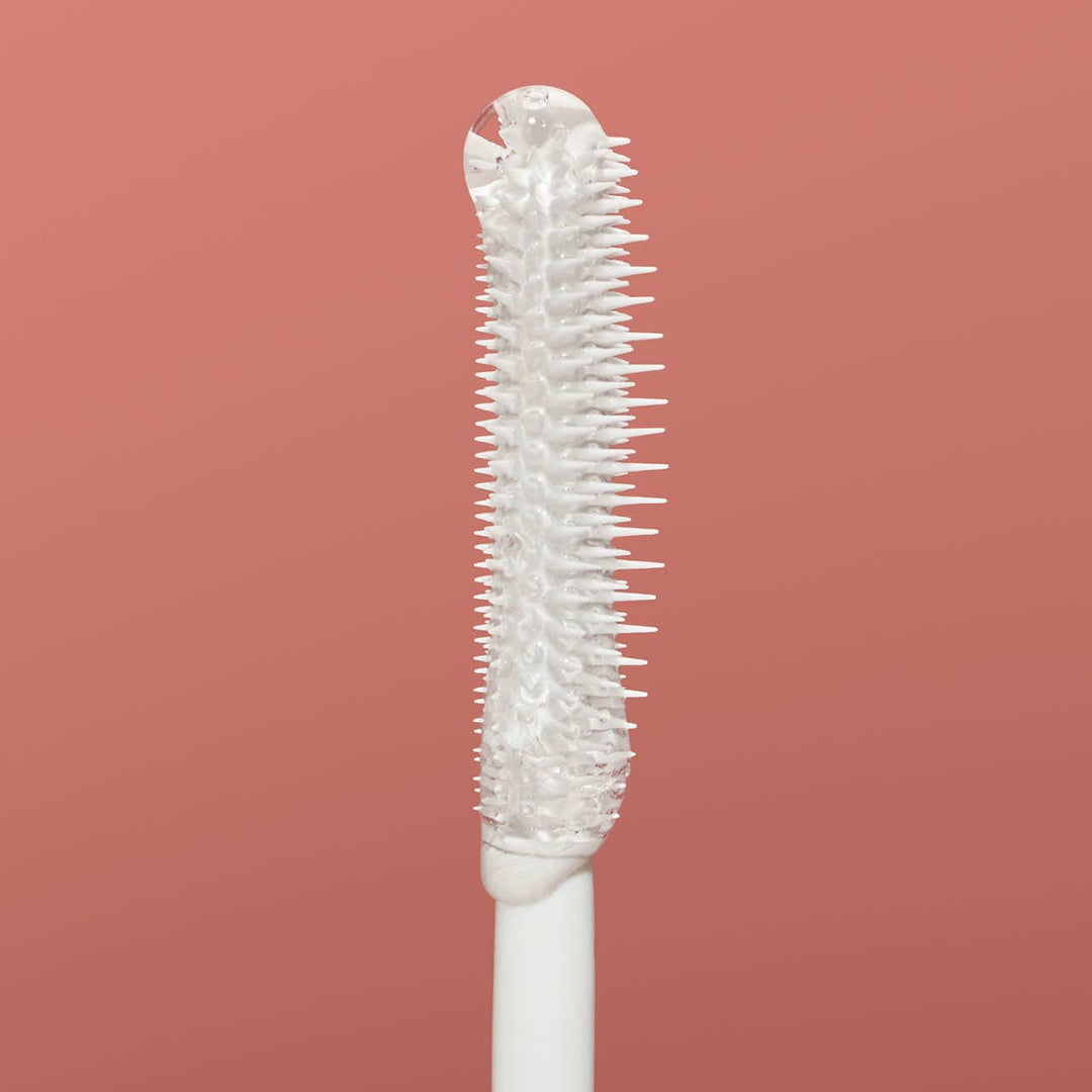 Bristle brush head on a white handle against a pink background