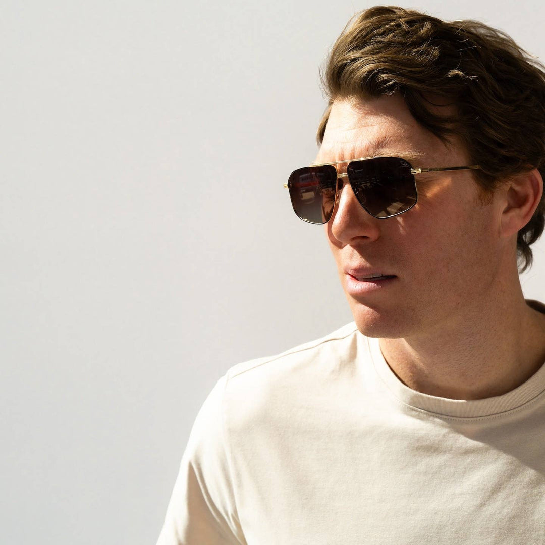 Man wearing sunglasses and a white shirt against a light background