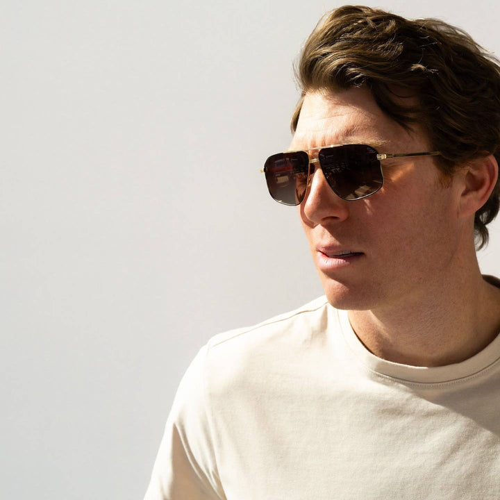 Man wearing sunglasses and a white shirt against a light background