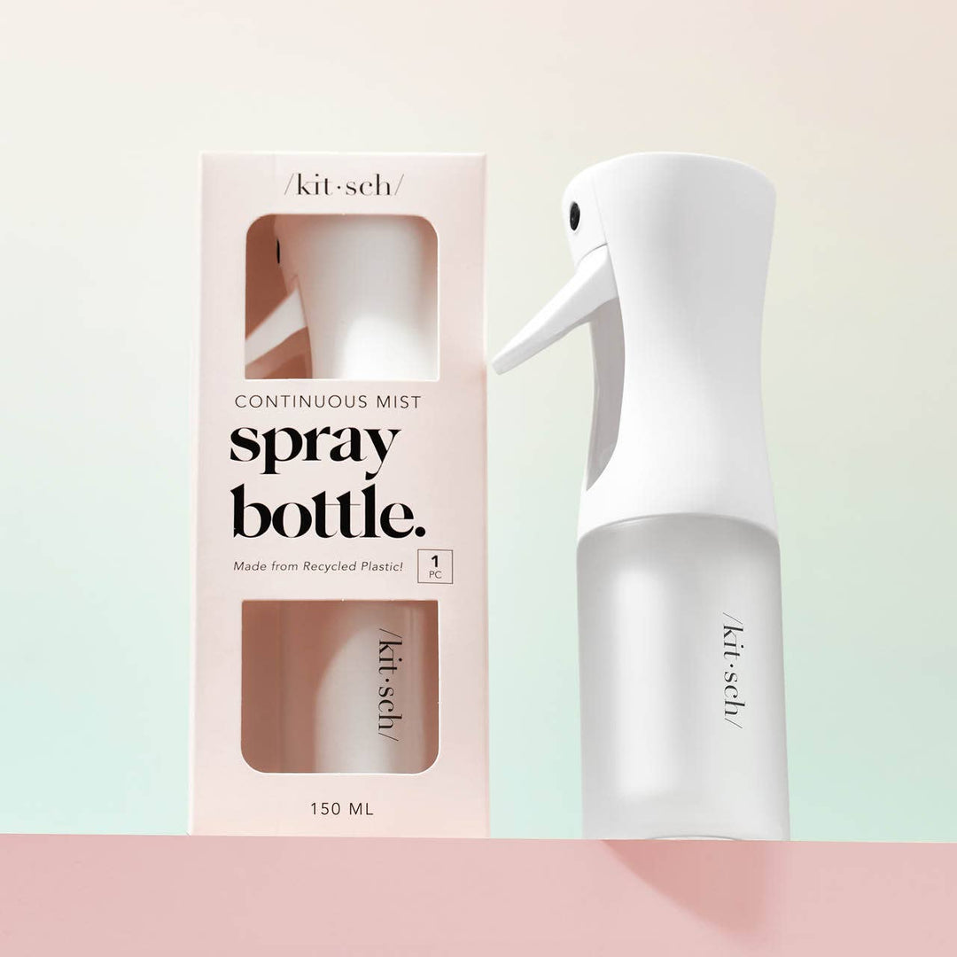 White spray bottle with packaging on a light pink background